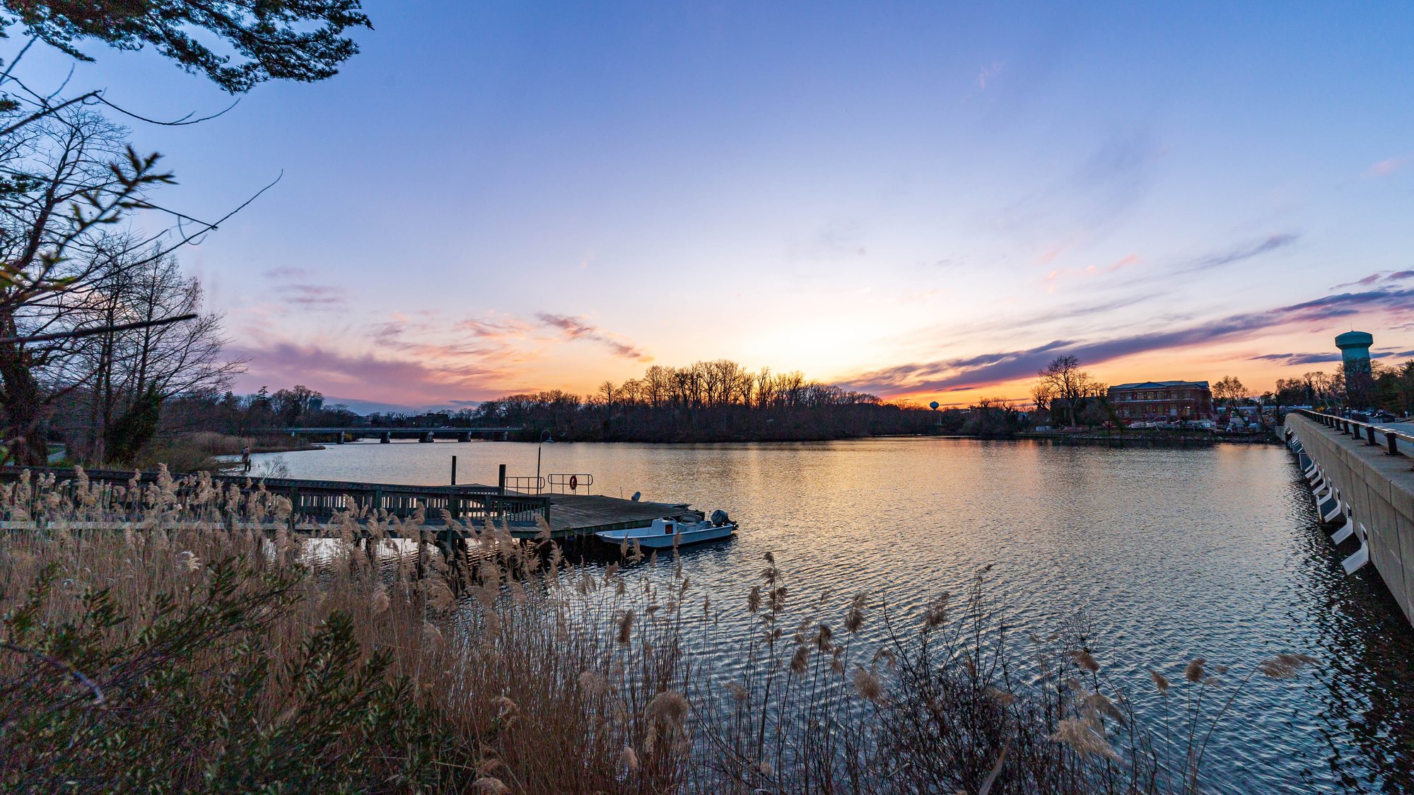 Sunset over a creek in Annapolis, with a dock and reeds in the foreground