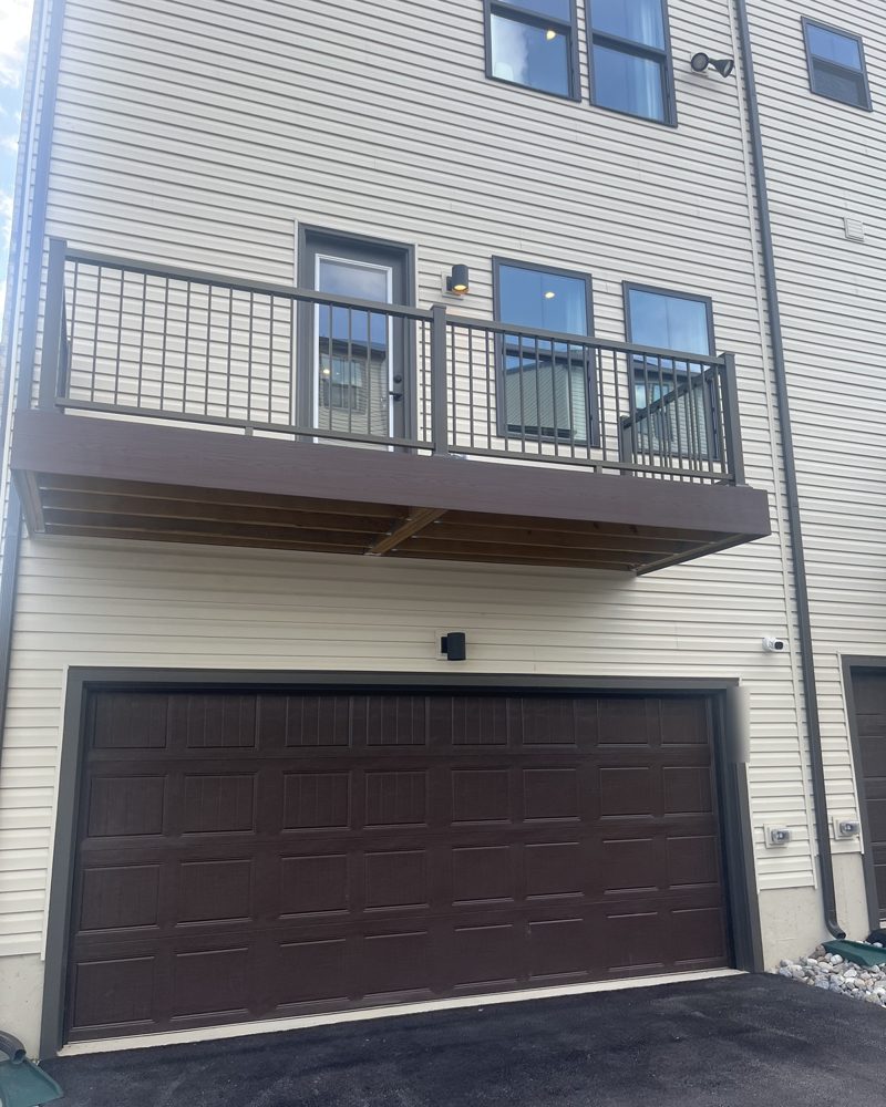 The back of a new townhome with a balcony over a two-car garage