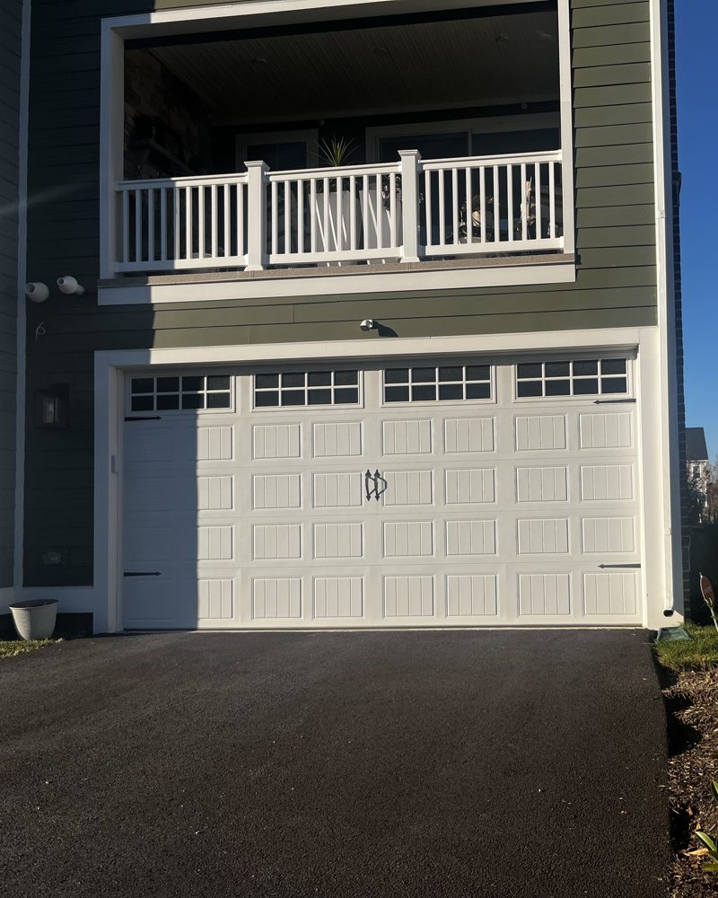 A two-car garage under a covered balcony on a new home
