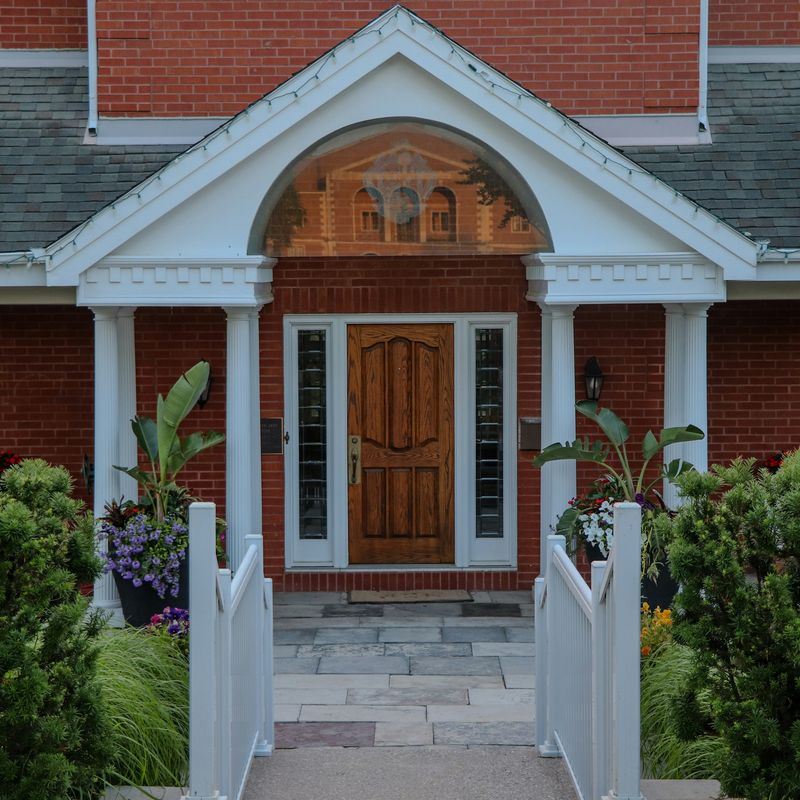 A brick house with a white portico and a wood front door